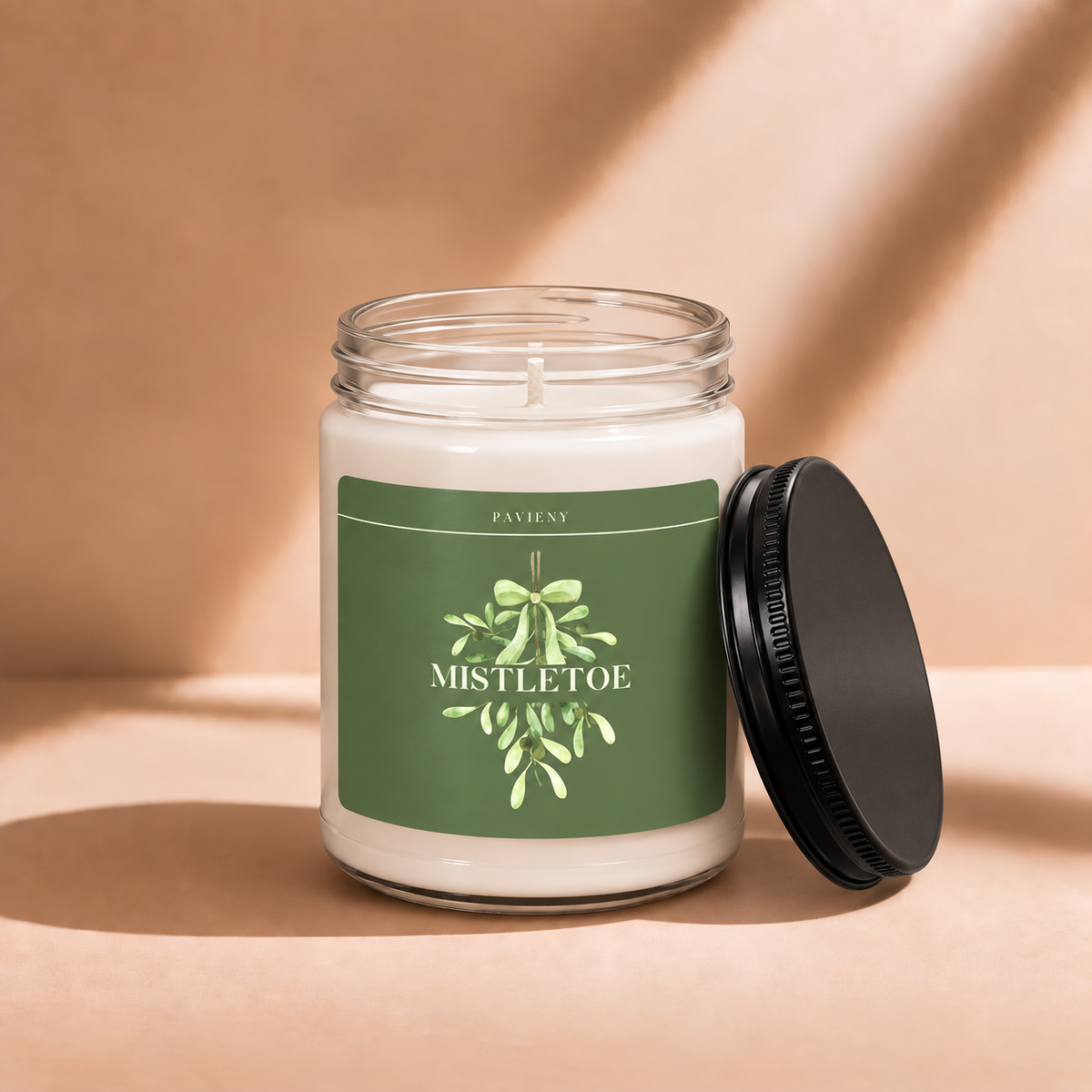 Open 9oz Mistletoe scented soy candle with the black lid beside the clear glass jar.