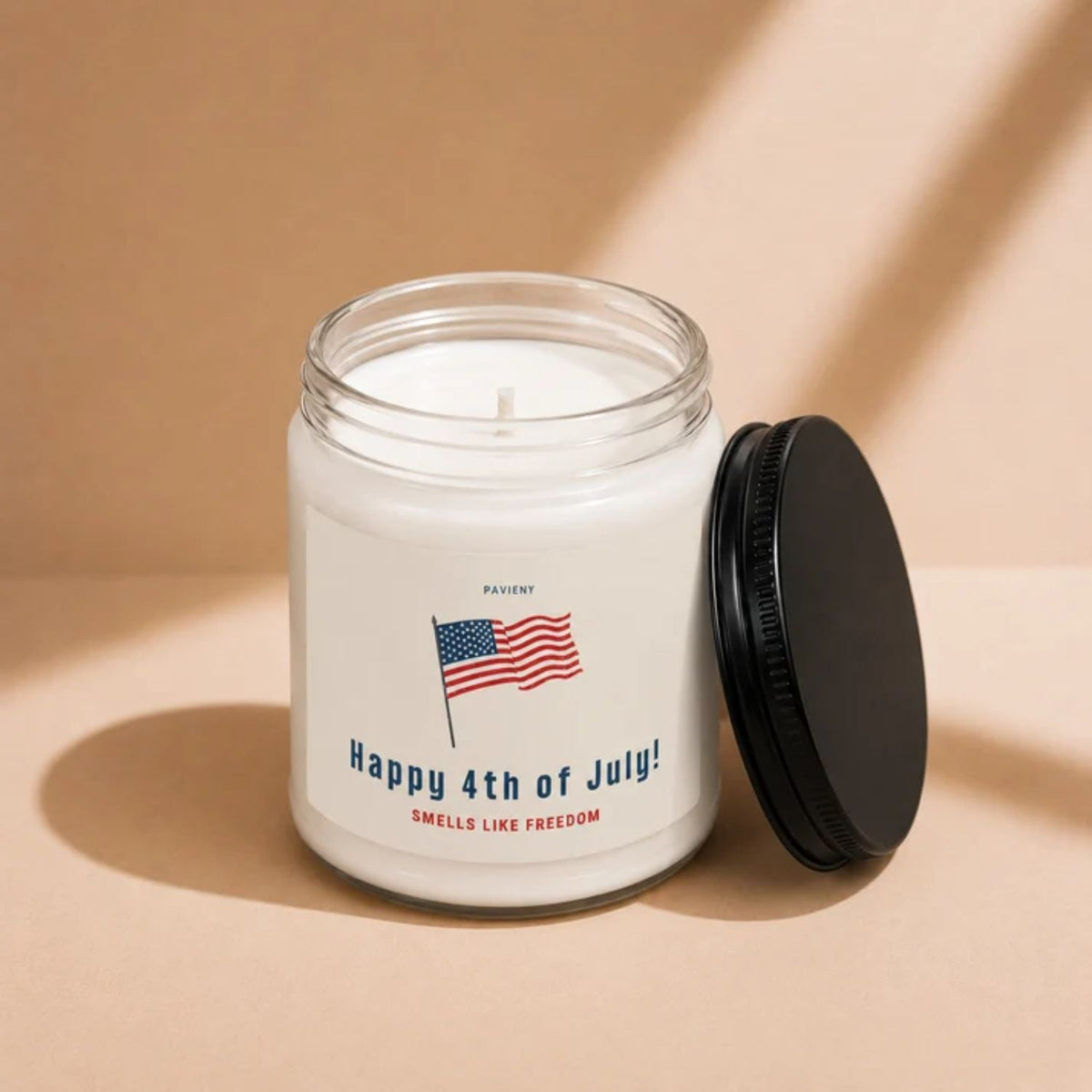 Open 9oz Smells Like Freedom scented soy candle with the black lid beside the clear glass jar.