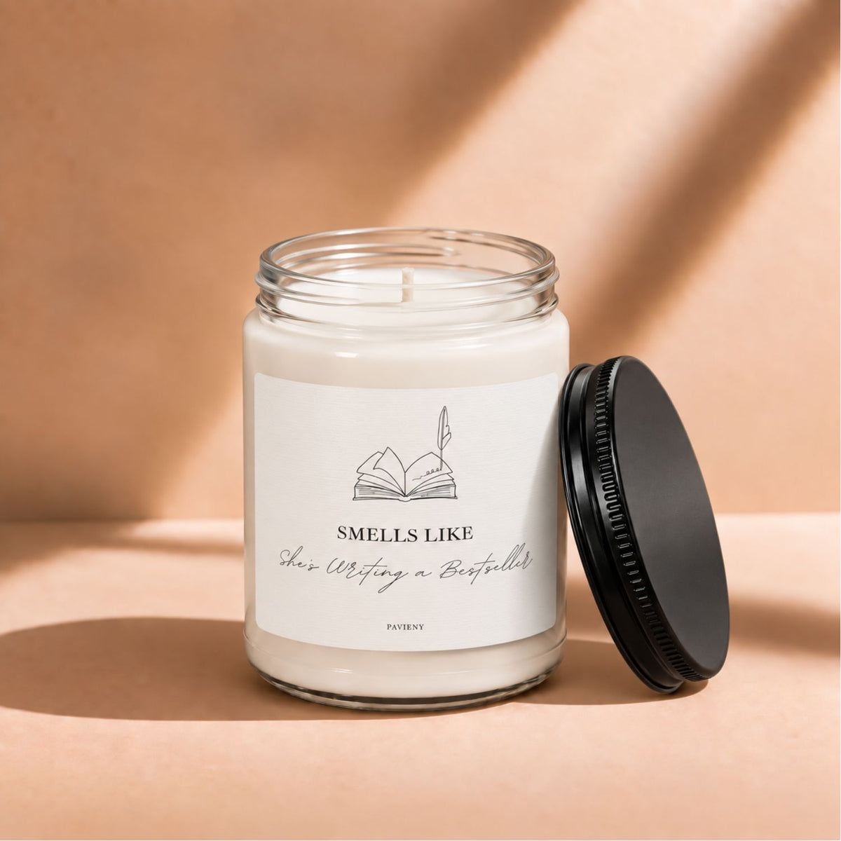 Open 9oz Writing a Bestseller candle with the black lid beside the glass jar.